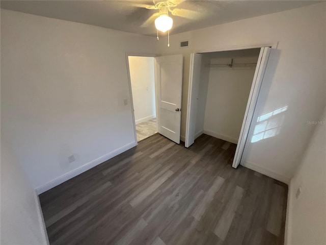 unfurnished bedroom with dark hardwood / wood-style flooring, a closet, and ceiling fan