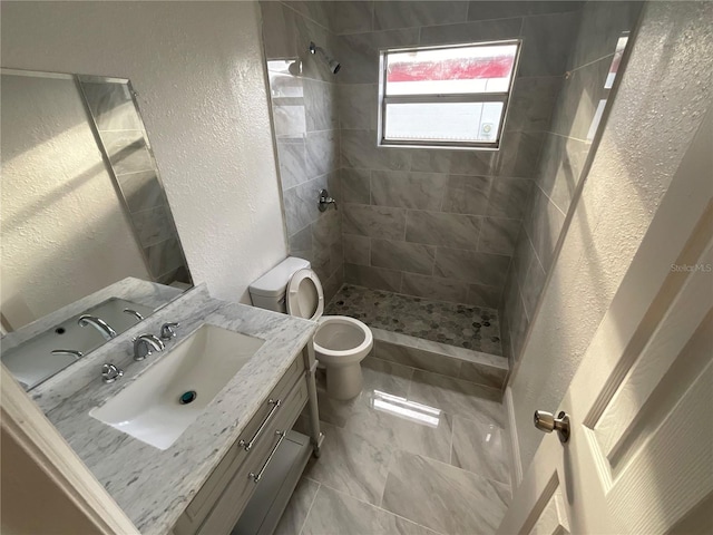 bathroom featuring toilet, vanity, and tiled shower