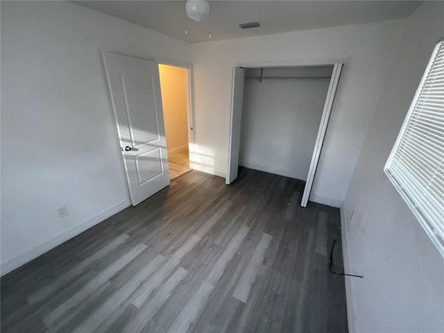 unfurnished bedroom featuring a closet and dark wood-type flooring