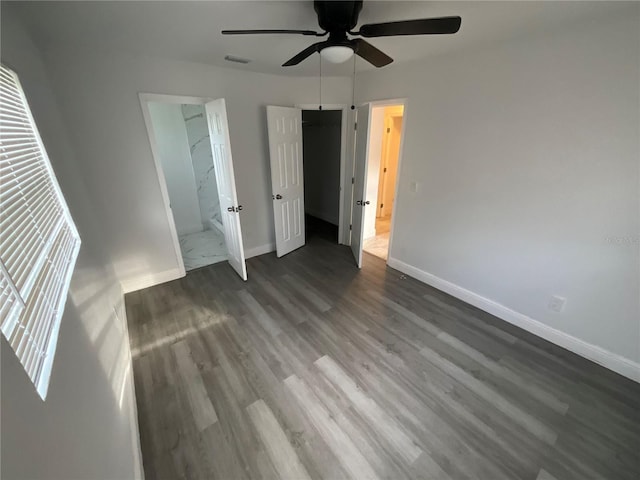 unfurnished bedroom with dark wood-type flooring, ceiling fan, and connected bathroom