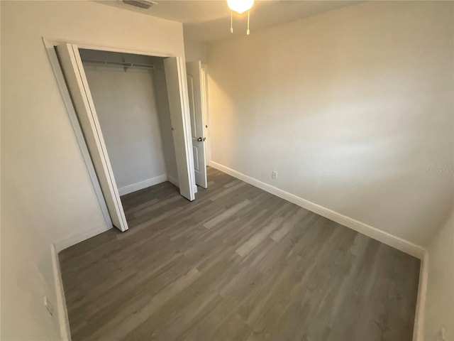 unfurnished bedroom featuring a closet and dark hardwood / wood-style flooring