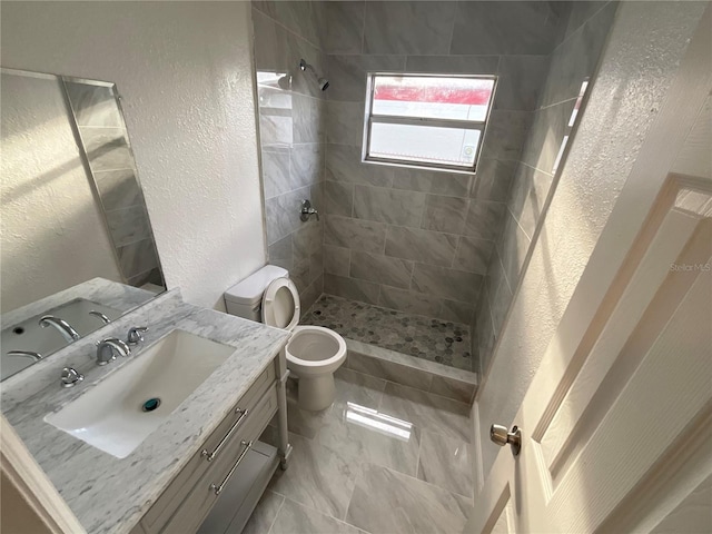 bathroom featuring vanity, a tile shower, and toilet