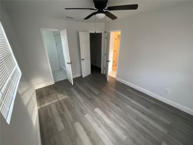 unfurnished bedroom with dark wood-type flooring, ensuite bathroom, and ceiling fan