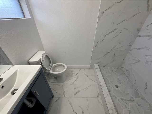 bathroom with vanity, a tile shower, and toilet