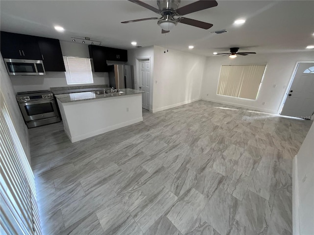 kitchen with a center island, stainless steel appliances, sink, and ceiling fan