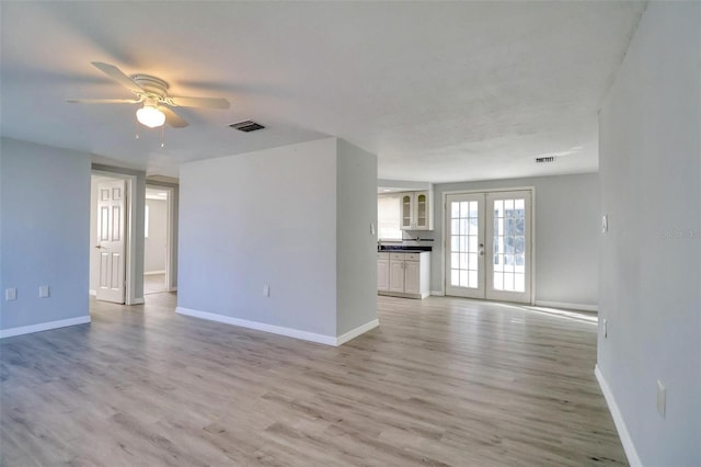 spare room with ceiling fan, light wood-type flooring, and french doors