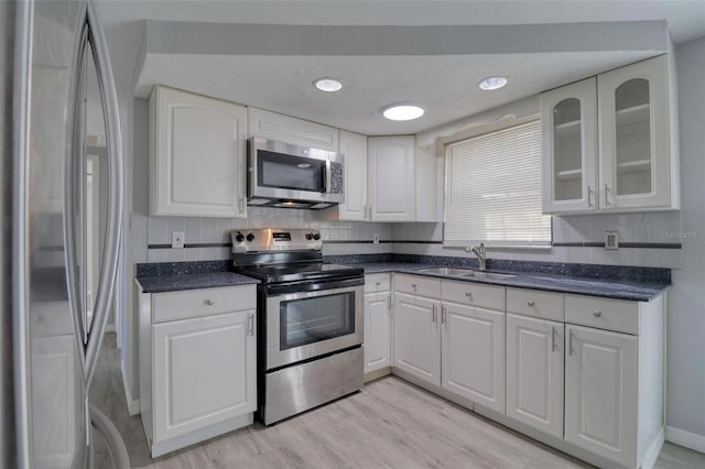 kitchen with sink, white cabinets, light hardwood / wood-style floors, and appliances with stainless steel finishes