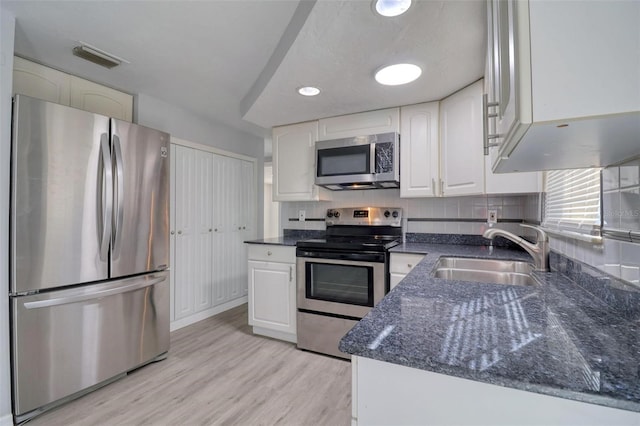 kitchen featuring decorative backsplash, appliances with stainless steel finishes, light wood-type flooring, sink, and white cabinets