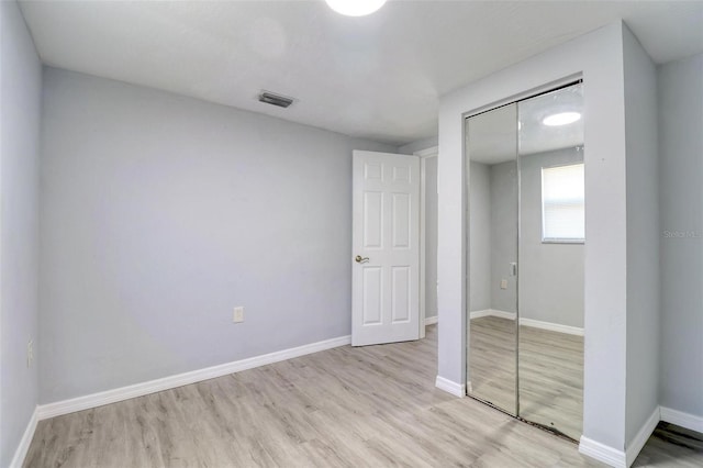 unfurnished bedroom with light wood-type flooring and a closet