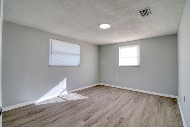 spare room featuring light hardwood / wood-style flooring and a textured ceiling