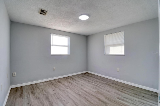 empty room with a textured ceiling and light wood-type flooring