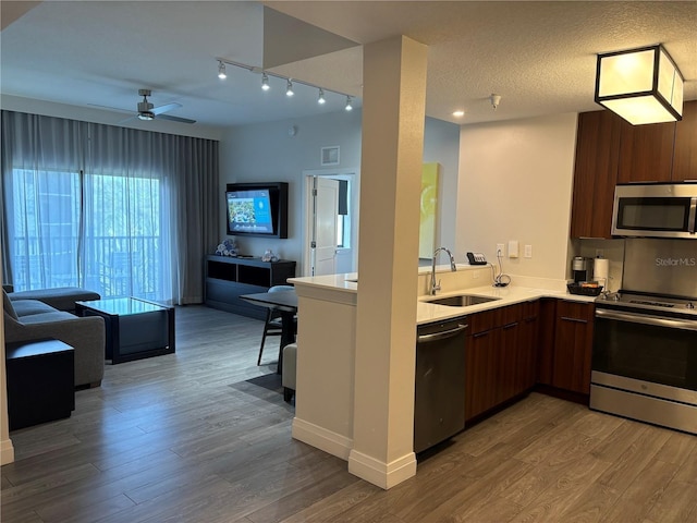 kitchen featuring hardwood / wood-style flooring, kitchen peninsula, stainless steel appliances, sink, and a textured ceiling