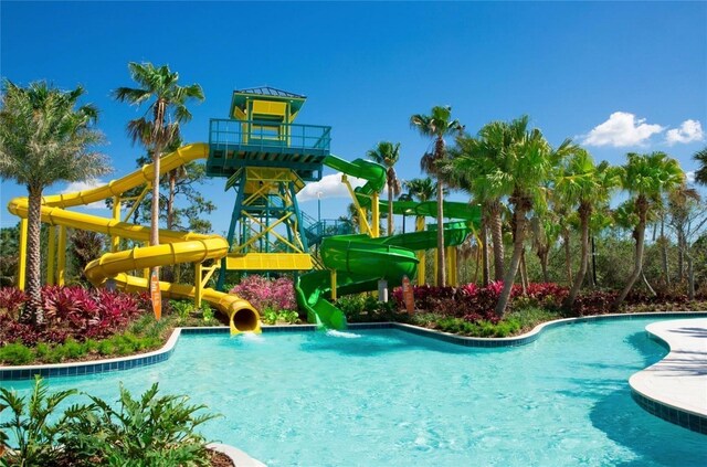 view of pool with a water slide and a playground