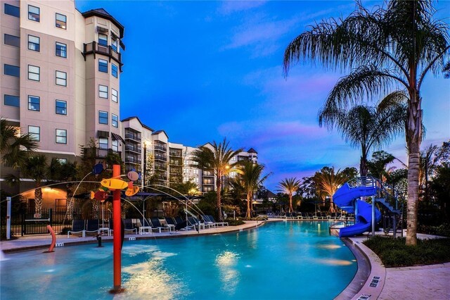 pool at dusk with a water slide and pool water feature