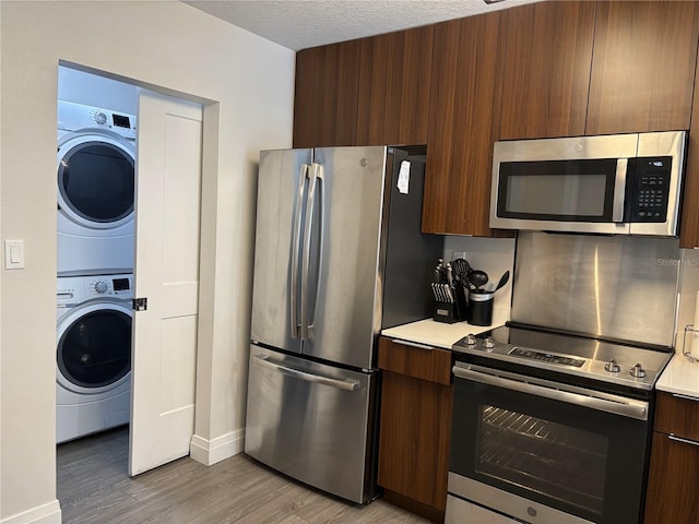 14501 Grove Resort Ave Unit 2608, Winter Garden, FL 34787 - kitchen with stainless steel appliances, modern cabinets, stacked washer and clothes dryer, light countertops, and light wood-type flooring