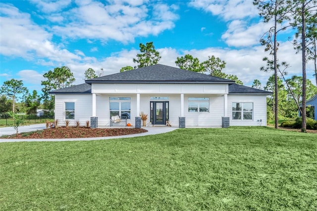back of property with a lawn, roof with shingles, and covered porch
