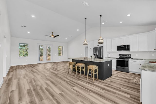 kitchen featuring white cabinets, hanging light fixtures, a kitchen island, appliances with stainless steel finishes, and light hardwood / wood-style floors