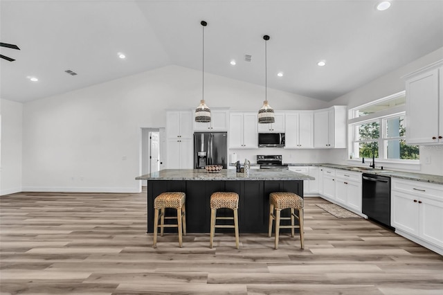 kitchen featuring a center island, white cabinets, light stone countertops, and stainless steel appliances