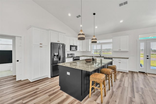 kitchen featuring light hardwood / wood-style flooring, a center island, white cabinets, pendant lighting, and appliances with stainless steel finishes