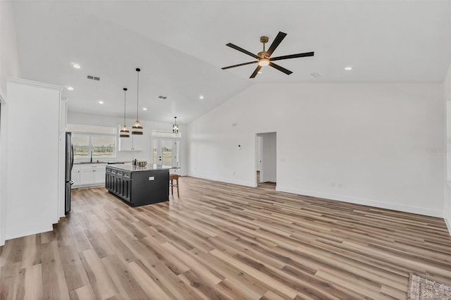 unfurnished living room with sink, ceiling fan, high vaulted ceiling, and light hardwood / wood-style flooring