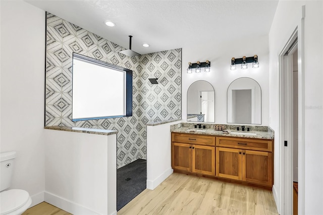 bathroom featuring toilet, vanity, hardwood / wood-style floors, a shower, and tile walls