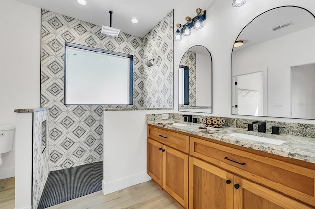 bathroom featuring vanity, toilet, walk in shower, and tile walls