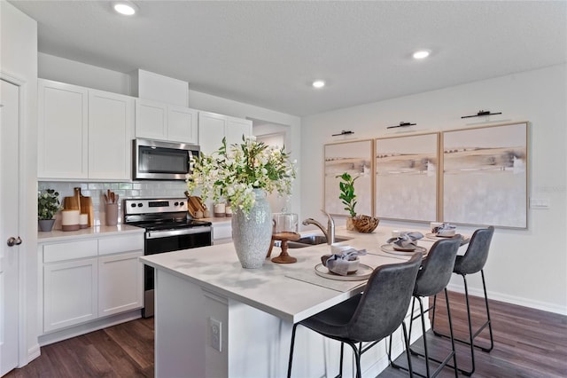 kitchen with sink, white cabinets, stainless steel appliances, and an island with sink