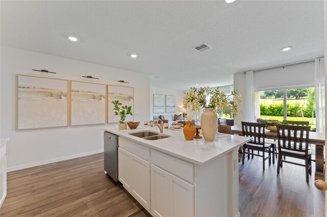 kitchen featuring hardwood / wood-style floors, an island with sink, white cabinetry, dishwasher, and sink