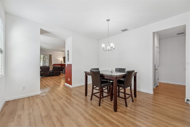 dining space with an inviting chandelier and light hardwood / wood-style flooring