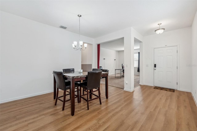 dining space featuring light hardwood / wood-style flooring and a chandelier