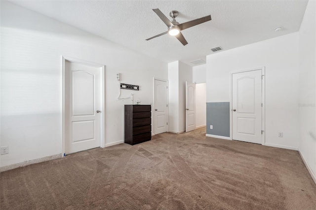 unfurnished bedroom with ceiling fan, light carpet, and a textured ceiling