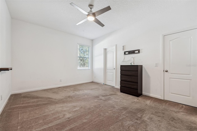 unfurnished bedroom with a textured ceiling, light colored carpet, and ceiling fan