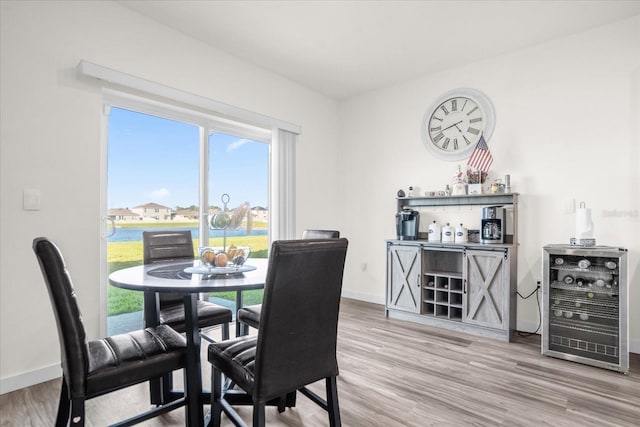 dining area featuring hardwood / wood-style floors, beverage cooler, and a water view