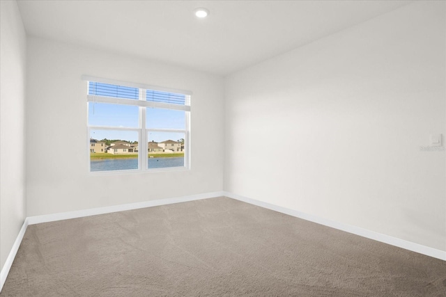 unfurnished room featuring a water view and carpet flooring