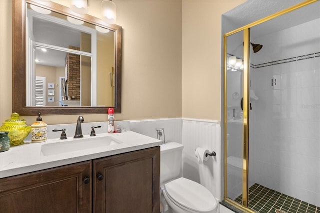 bathroom with a shower with door, vanity, and toilet