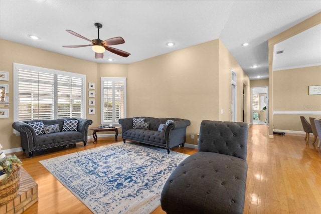 living room featuring ceiling fan, ornamental molding, and light hardwood / wood-style flooring