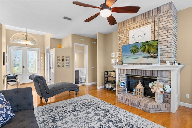 living room featuring a fireplace, french doors, light wood-type flooring, and ceiling fan