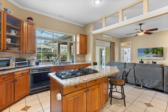 kitchen with a kitchen island, gas cooktop, black dishwasher, sink, and light stone countertops