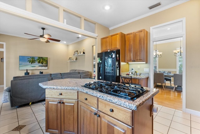 kitchen featuring light tile patterned flooring, black appliances, a center island, and ornamental molding