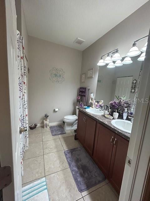 bathroom with toilet, vanity, and tile patterned floors