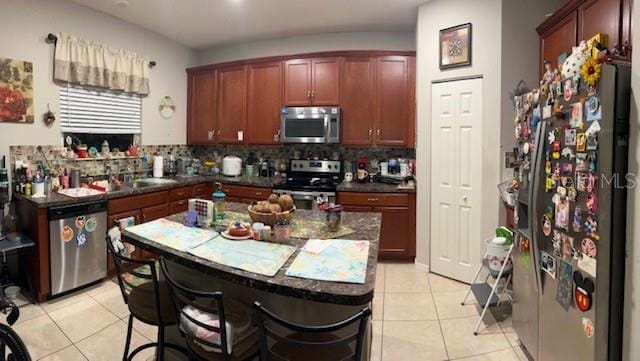 kitchen featuring tasteful backsplash, a center island, light tile patterned floors, and stainless steel appliances