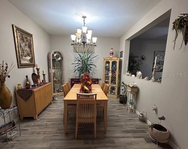 dining room featuring dark wood-type flooring, a chandelier, and a textured ceiling