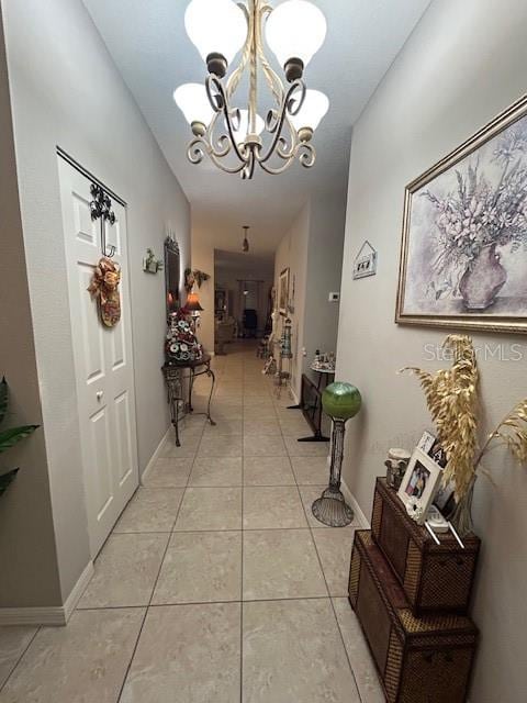 hallway featuring light tile patterned floors and a notable chandelier