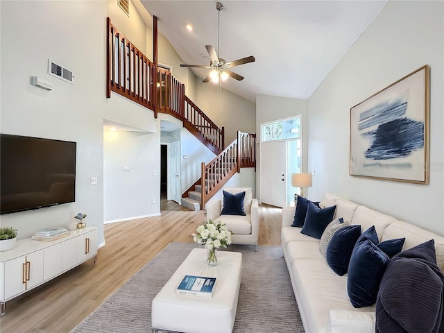 living room with ceiling fan, high vaulted ceiling, and light wood-type flooring