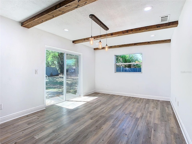 unfurnished room featuring dark hardwood / wood-style floors, beam ceiling, and plenty of natural light