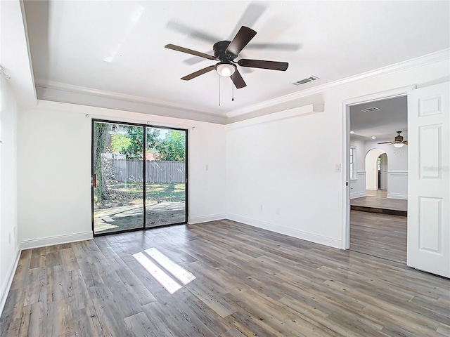 spare room with dark wood-type flooring, crown molding, and ceiling fan