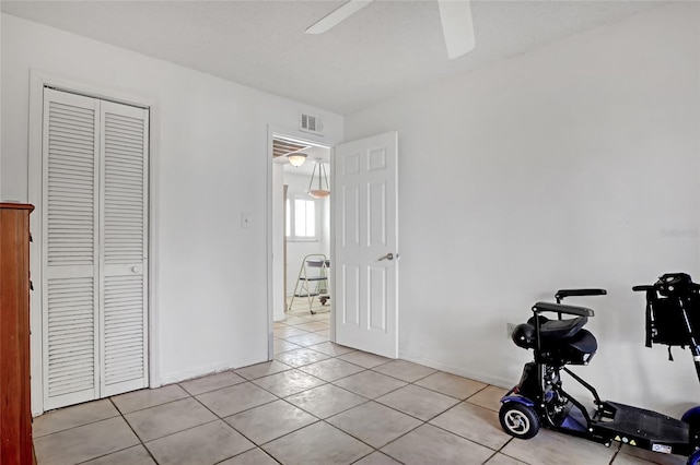 exercise room featuring ceiling fan and light tile patterned floors