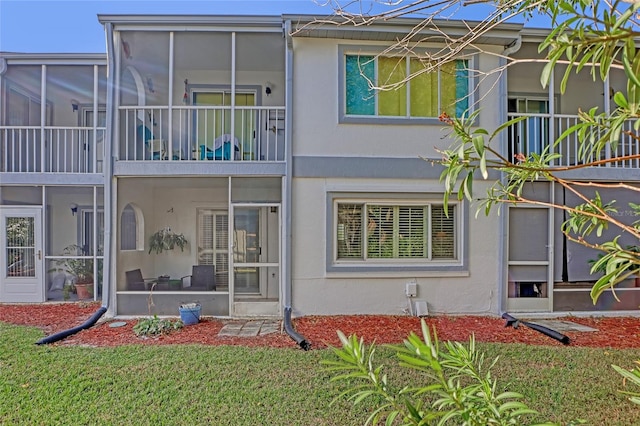 rear view of property featuring a balcony and a lawn