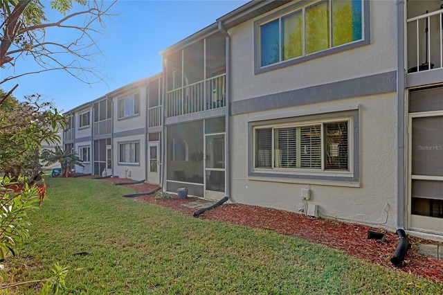 rear view of property featuring a yard and a sunroom