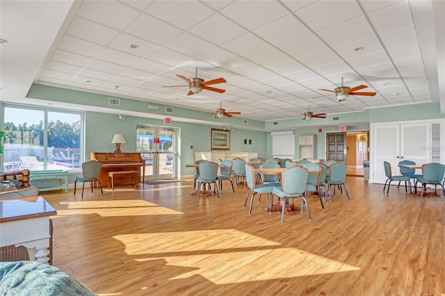 dining area with french doors, a paneled ceiling, light wood-type flooring, and ceiling fan